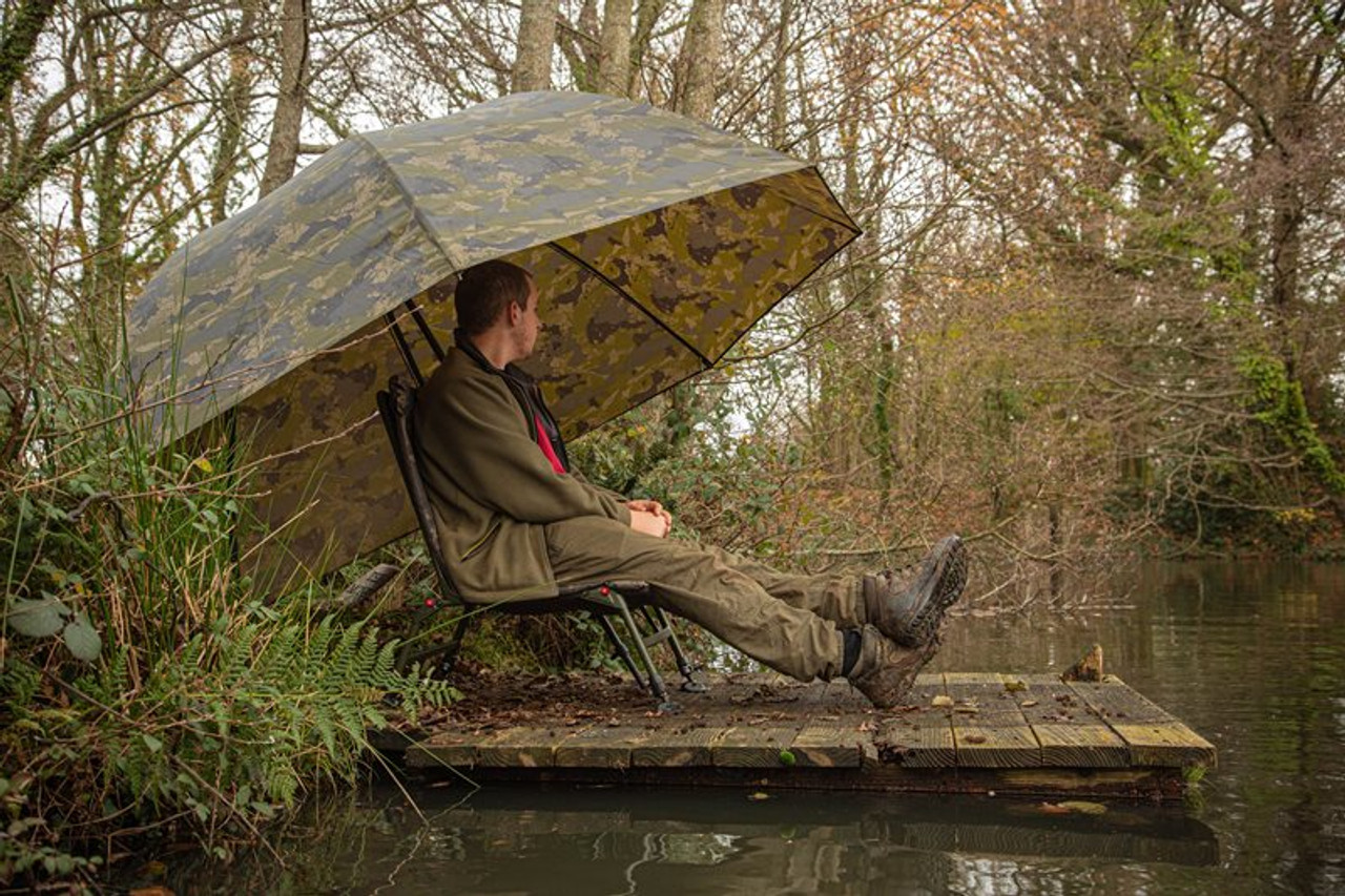 A fisherman sitting under the Solar Undercover Camo 60 Inch Brolly